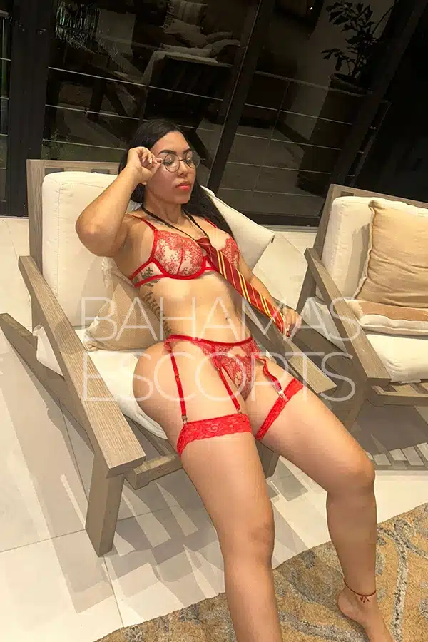 Seductive woman in elegant red lingerie posing confidently in a luxury bedroom